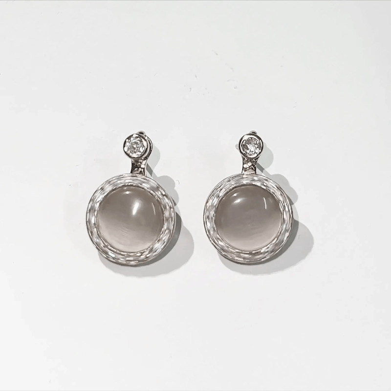 Pair of silver earrings with gemstones on a white background