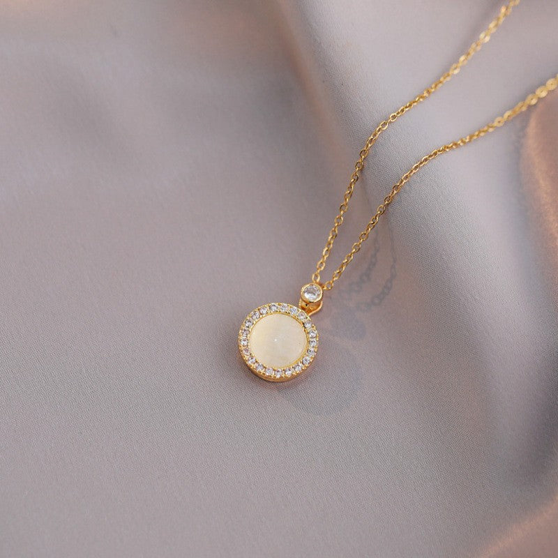 Gold necklace with a round pendant on a soft gray background