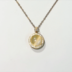 Gold necklace with a pendant featuring a yellow gemstone on a white background