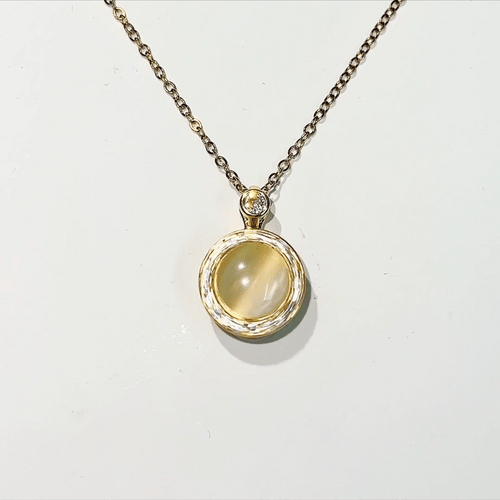 Gold necklace with a pendant featuring a yellow gemstone on a white background