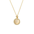 A gold chain necklace with a circular pendant featuring a central milky white stone surrounded by a halo of small clear stones, on a plain white background.