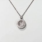 Silver necklace with a round pendant on a light gray background