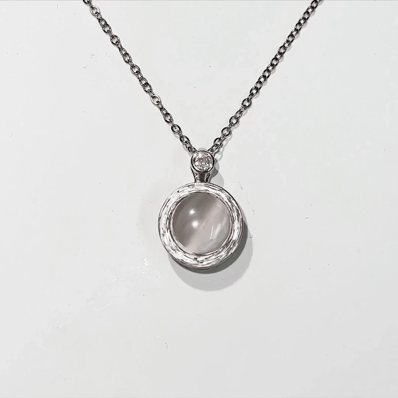 Silver necklace with a round pendant on a light gray background