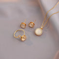 Gold jewelry set with round stones on a soft gray background