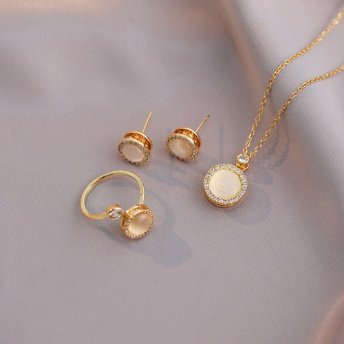 Gold jewelry set with round stones on a soft gray background