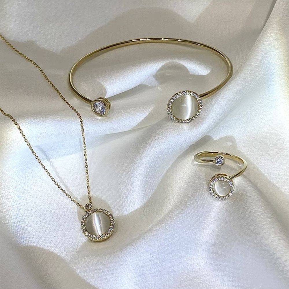 Gold jewelry set including necklace, bracelet, and rings on a white fabric background