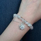 Bracelet with snowflake charm on a wrist against a dark blue background