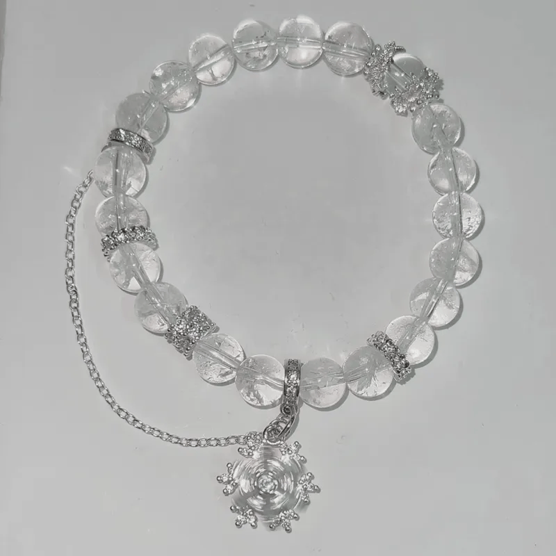 Necklace with clear beads and silver chain on a light gray background
