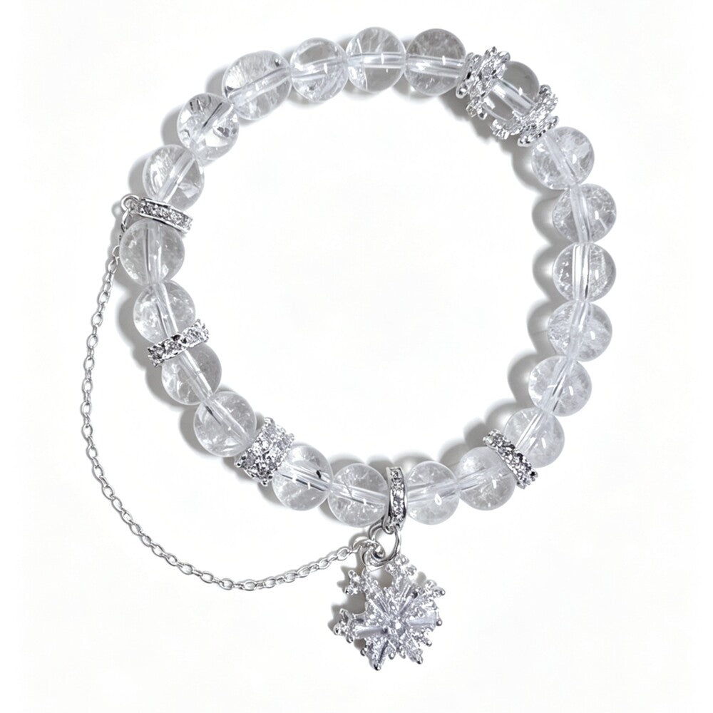 A clear crystal beaded bracelet with silver-toned chain and snowflake charms, displayed on a clean white background.