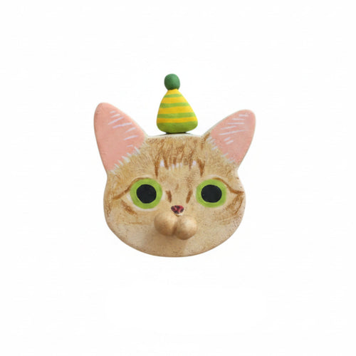 A novelty cat head mask or face covering featuring an orange tabby cat design with pink ears, large green eyes, and a small green and yellow striped party hat on top, shown against a plain white background.