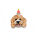A decorative dog head plaque or ornament featuring a fluffy tan and cream dog face with a small red party hat with white hearts and a yellow pom-pom, shown on a plain white background.
