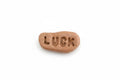 A small, irregularly shaped brown stone engraved with the word 'LUCK' on a plain white background.
