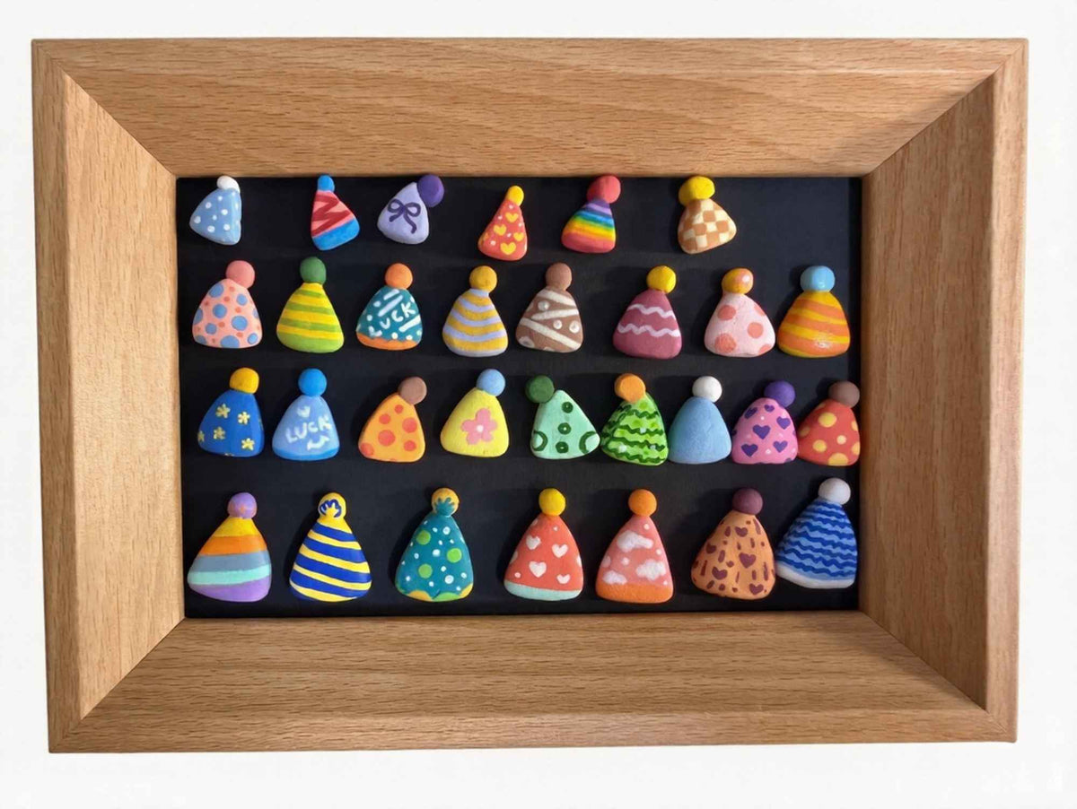 A framed art piece featuring thirty colorful, cone-shaped clay figures arranged in four rows on a black background, enclosed in a light oak wood frame.