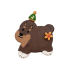 A small decorative figurine shaped like a Shiba Inu dog, painted in brown, tan, white, and orange, wearing a green and orange hat with a white bone symbol.