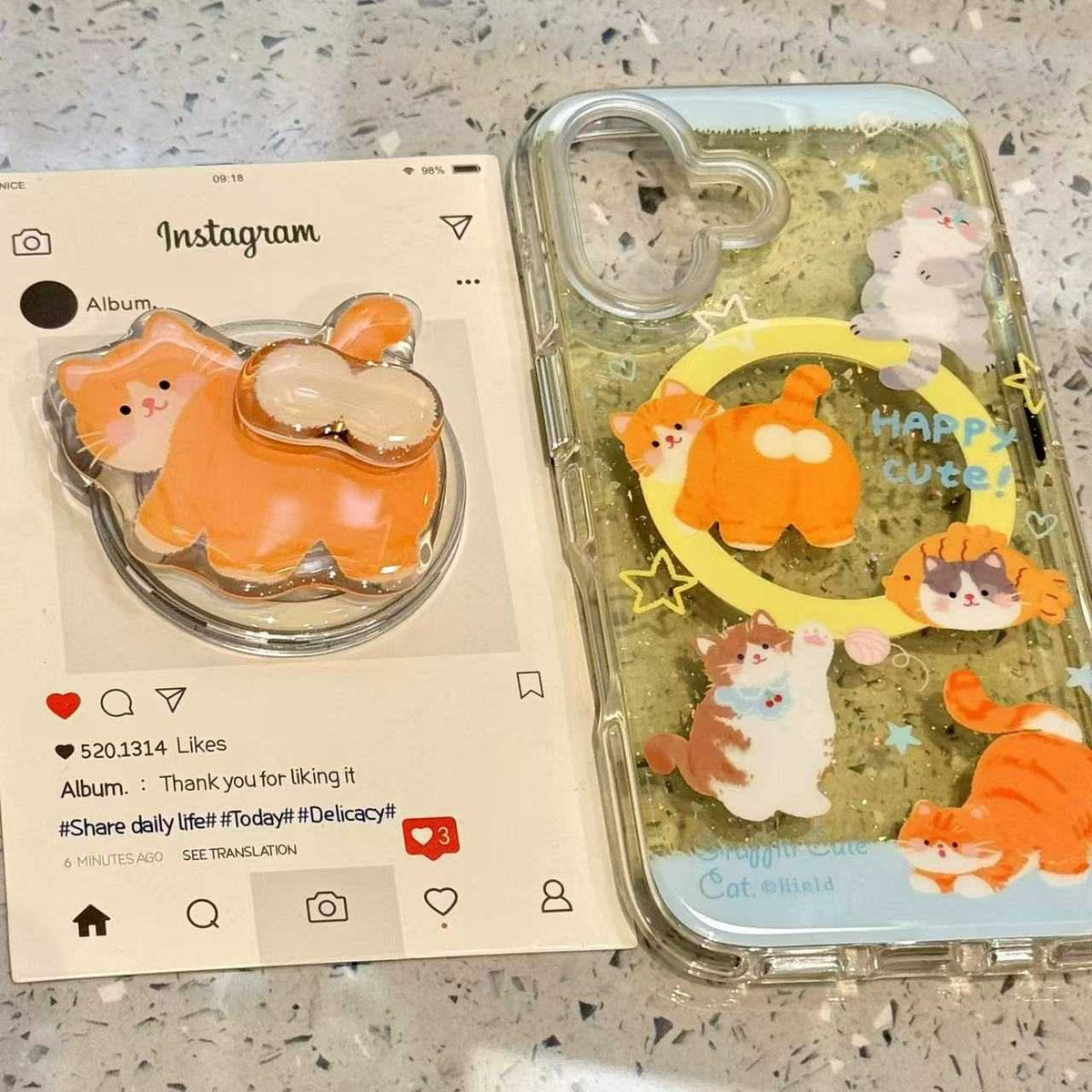 A clear phone case with glittery green background and multiple orange, cream, and white cat illustrations, shown next to its matching clear display stand. The stand features a large orange cat design with cream accents.