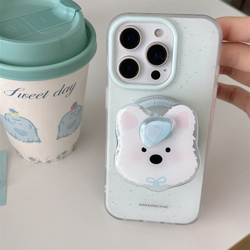 A close-up of a phone case being held by a hand, featuring a speckled pale mint green back with a bear-face pop socket and a matching camera-ring accent. A mint-tinted takeaway cup sits beside it on a light surface.