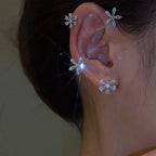 Close-up of an ear wearing snowflake-shaped earrings with a blurred background