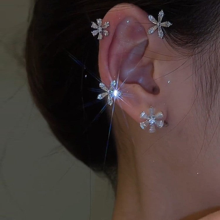 Close-up of an ear wearing snowflake-shaped earrings with a blurred background