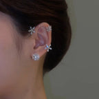 Close-up of an ear with floral earrings against a neutral background