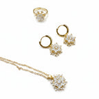 Gold jewelry set featuring a ring, hoop earrings, and pendant necklace, each adorned with a snowflake-shaped cluster of clear cubic zirconia stones on a white background.