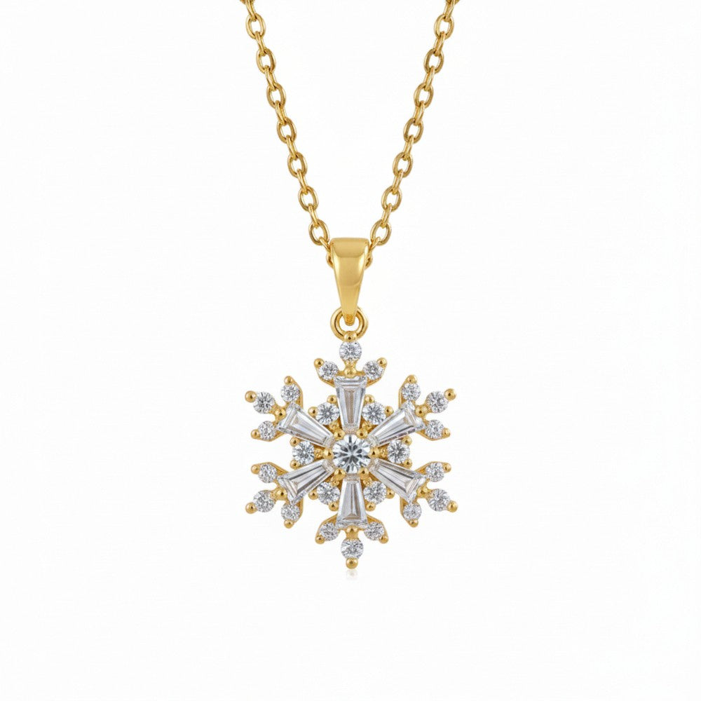 Gold necklace with a snowflake pendant on a white surface