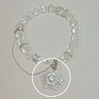 A clear crystal beaded bracelet with silver-toned chain and rhinestone accents, featuring a circular clear crystal pendant with a central clear stone, shown on a light neutral background.
