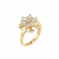 A gold ring featuring a snowflake-shaped cluster of clear baguette and round-cut stones, set on a plain white background.