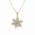 A gold snowflake pendant necklace adorned with clear crystals, suspended from a delicate gold chain against a plain white background.