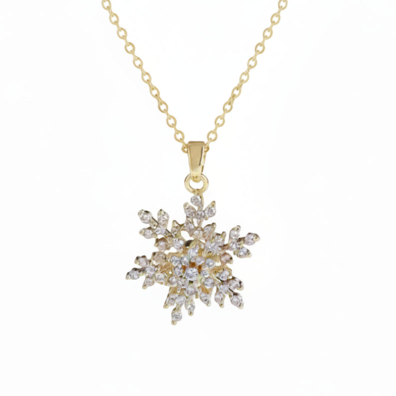 A gold snowflake pendant necklace adorned with clear crystals, suspended from a delicate gold chain against a plain white background.