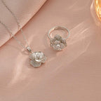 Silver flower-shaped necklace and ring on a pink fabric background