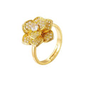 A gold flower ring with a central clear gemstone and small clear stones in the petals, shown on a plain white background.