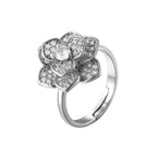 Silver flower-shaped ring with embedded diamonds on a white background