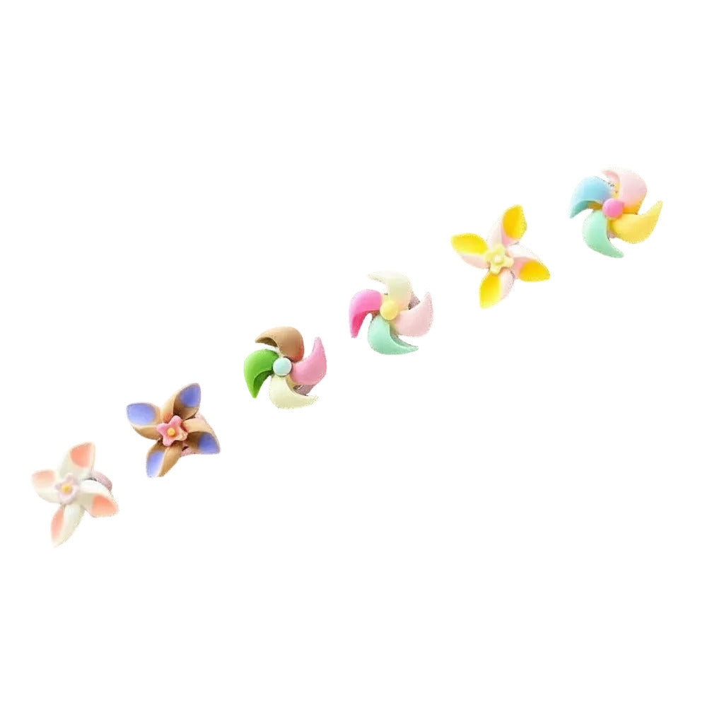 Six pastel-colored flower-shaped earrings arranged diagonally on a plain white background.