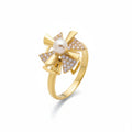 A gold ring featuring a bow design with a central white pearl and pavé-set clear stones, shown on a clean white background.