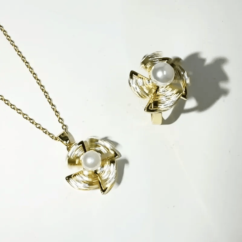 Gold-tone jewelry set featuring a matching necklace and stud earring, each with a textured spiral flower-like pendant set with a white faux pearl in the center, displayed on a white background.