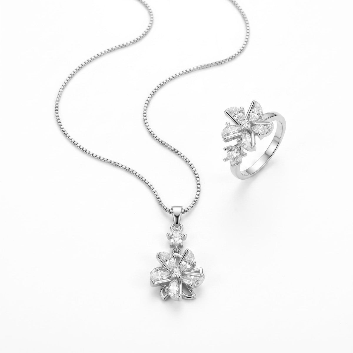 A silver-tone jewelry set featuring a delicate beaded chain necklace with a flower-shaped pendant and a matching flower ring, displayed on a clean white background.