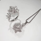 Silver jewelry set with turtle-shaped pendant and ring on a white background