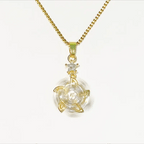 A gold chain necklace with a clear circular pendant featuring a gold four-petal design and a small clear gemstone star accent above it, shown on a plain white background.