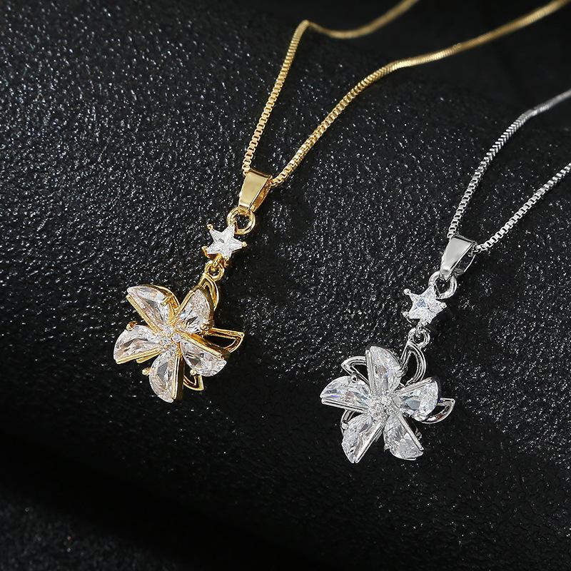 Two floral pendant necklaces, one gold and one silver, on a black background.