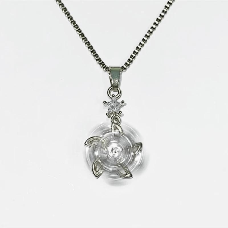 A silver-tone chain necklace with a clear circular pendant featuring a central starburst or ninja-star design, shown on a plain light gray background.